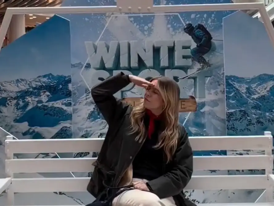 Creator sitting on a white bench in front of the Winter Sport installation at Bicocca Village