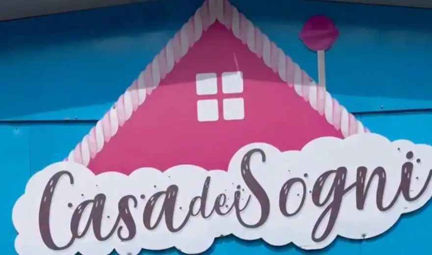Enseigne « Casa dei Sogni » avec une maisonnette rose sur un mur bleu clair